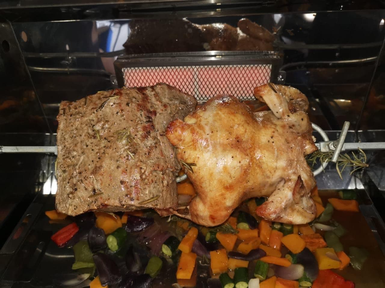 Rolled beef and a whole chicken roasting over the gas burner