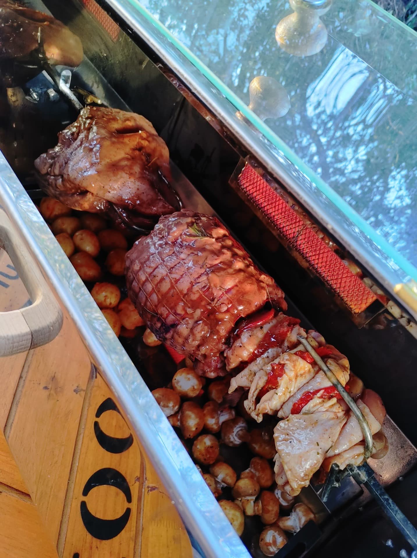 Lamb and rolled pork on the spit with baby potatoes below