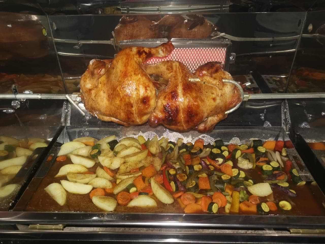 Golden roasted chickens turning on a Spitbraaiers spit